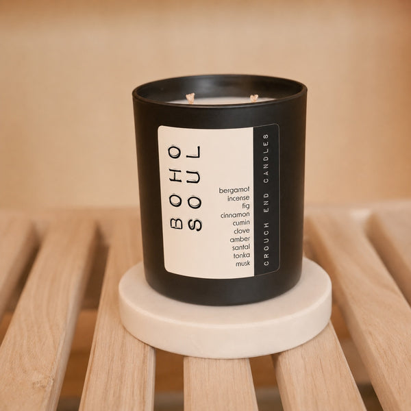 Black candle labeled 'BOHO SOUL' on a wooden stool with a neutral background