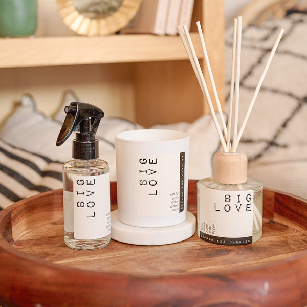 Three 'BIG LOVE' products on a wooden tray with a blurred background