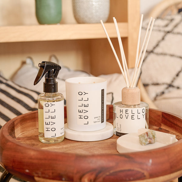 Decorative items including a room spray bottle, candle, and diffuser on a wooden tray with 'HELLO LOVELY' branding.