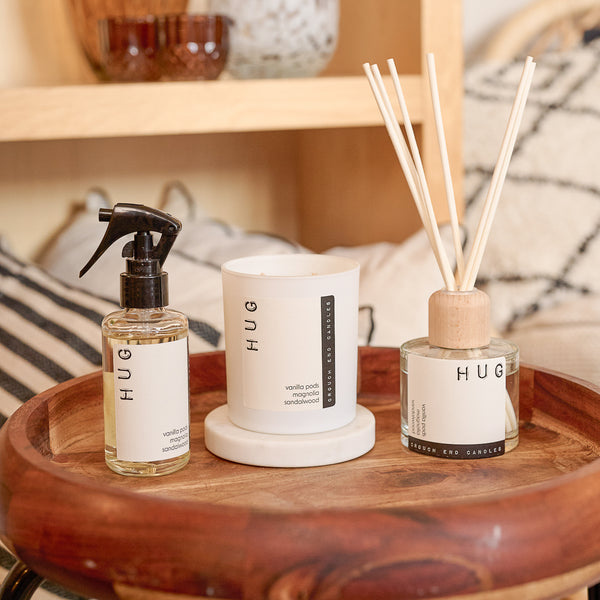 Three 'HUG' products on a wooden tray with a blurred background