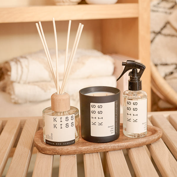 Three 'KISS KISS' products on a wooden tray with a blurred background