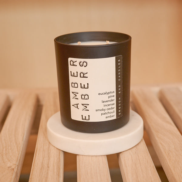 Candle with 'Amber Embers' label on a wooden surface