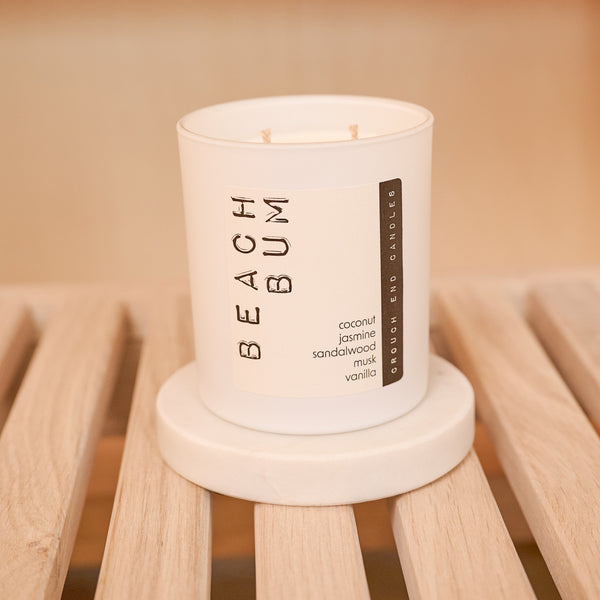 Candle labeled 'Beach Bum' on a wooden surface
