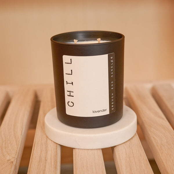 Candle labeled 'CHILL' on a wooden surface with a blurred background