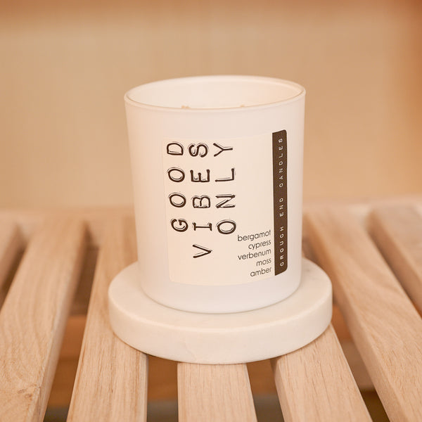 Candle with 'Good Vibes Only' text on a wooden surface