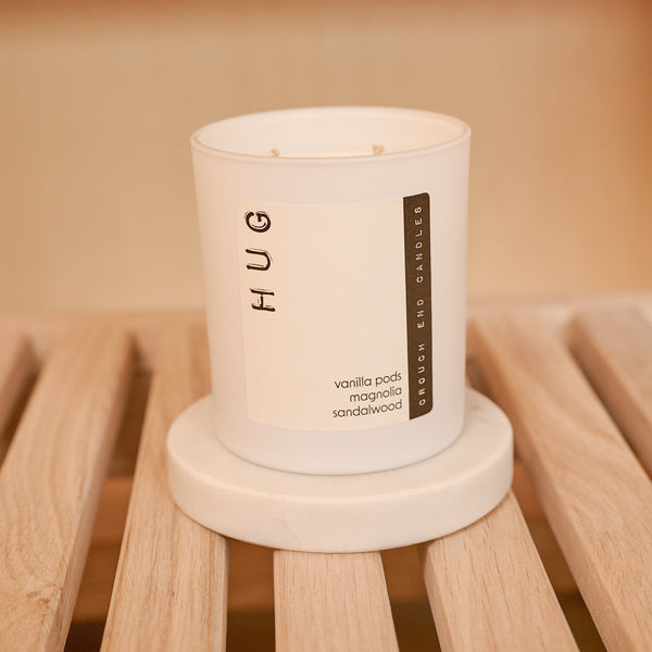 Candle labeled 'HUG' on a wooden surface with a warm background