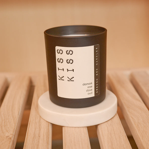 Candle with 'KISS KISS' label on a wooden surface