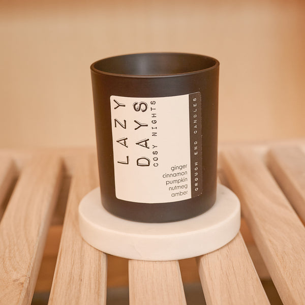 Candle with 'Lazy Days' label on a wooden surface
