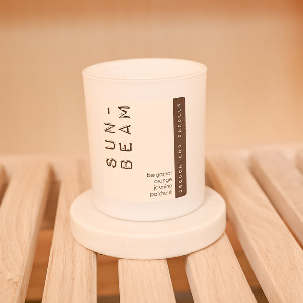 Candle labeled 'Sunbeam' on a wooden stand with a warm background